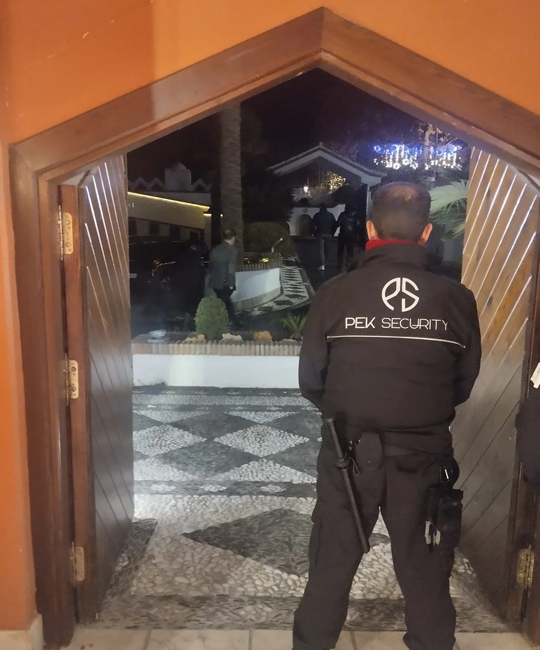 Vigilante de PEK SECURITY identificado por el uniforme supervisando el acceso a un recinto