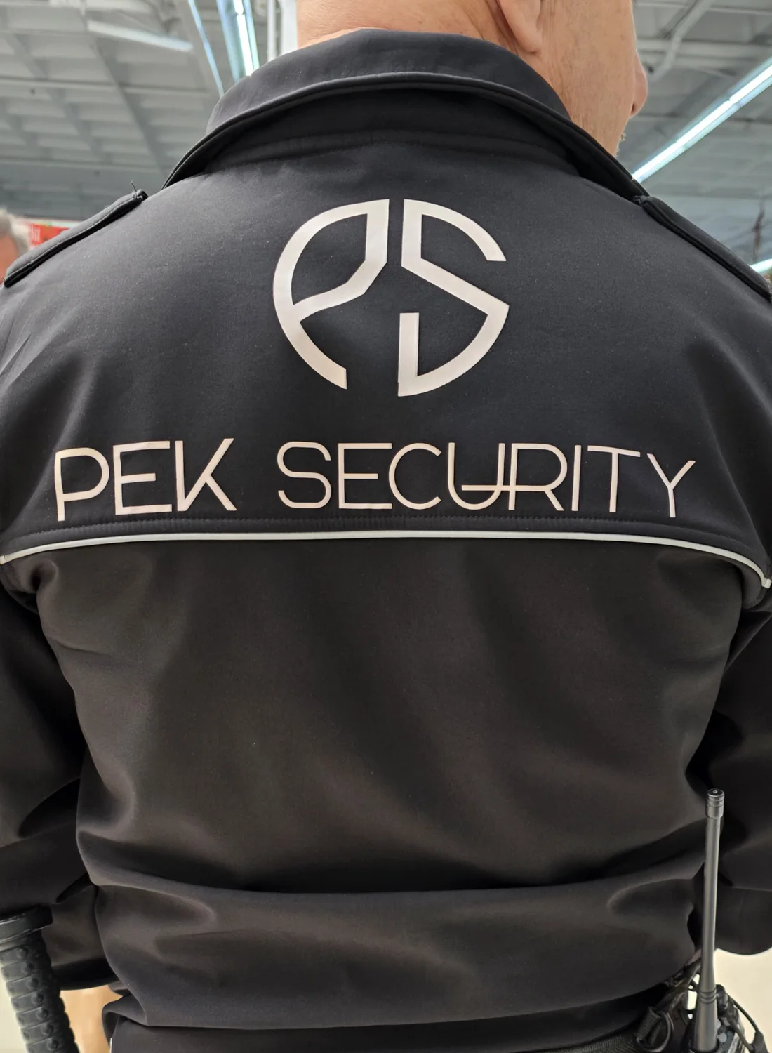 Detalle real del uniforme de PEK SECURITY con el logotipo en la espalda